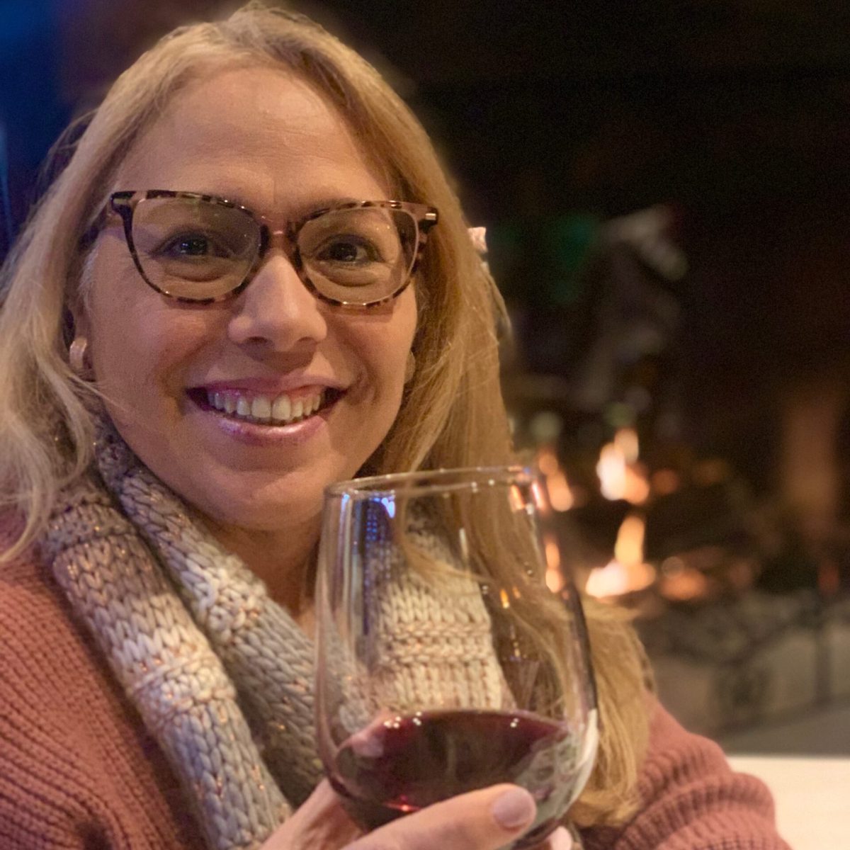 a woman wearing glasses holding a glass of wine